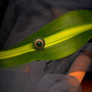 Green white stone-studded circular finger ring.